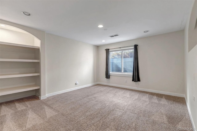 unfurnished room with built in shelves, recessed lighting, carpet flooring, visible vents, and baseboards