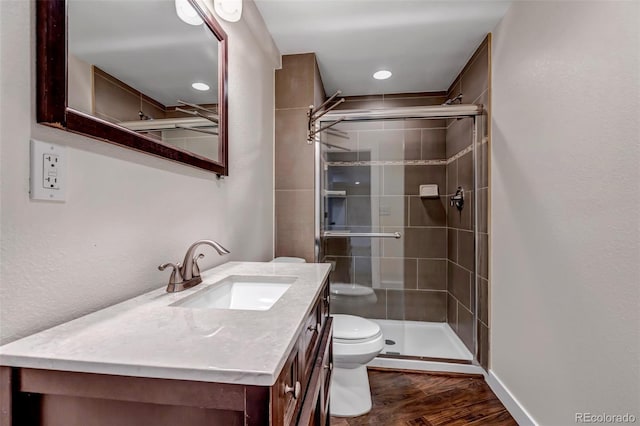 bathroom with toilet, a shower stall, wood finished floors, and vanity