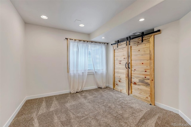 spare room featuring recessed lighting, carpet flooring, baseboards, and a barn door