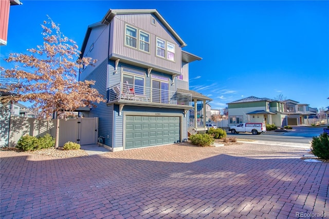 view of front facade with decorative driveway, an attached garage, fence, and a gate