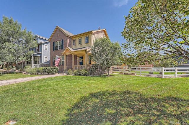 view of front facade with brick siding, a front lawn, and fence