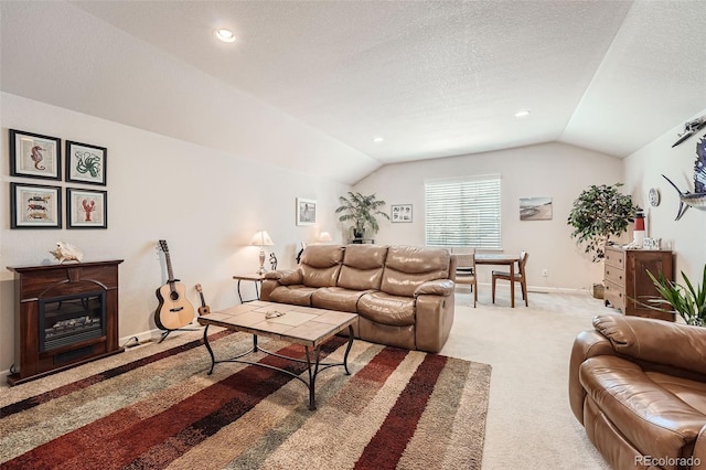 living area featuring baseboards, lofted ceiling, light carpet, a glass covered fireplace, and a textured ceiling