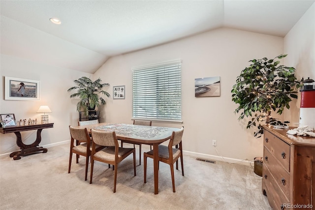 dining room with baseboards, lofted ceiling, and light colored carpet