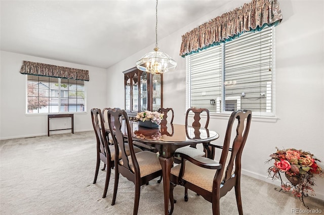 dining space with a chandelier, light colored carpet, and baseboards