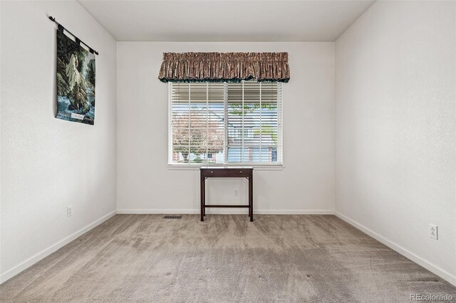 spare room featuring carpet floors and baseboards
