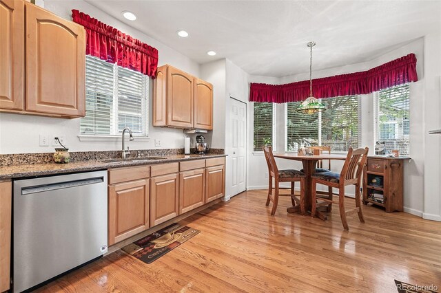 kitchen featuring stainless steel dishwasher, a sink, light wood finished floors, recessed lighting, and hanging light fixtures