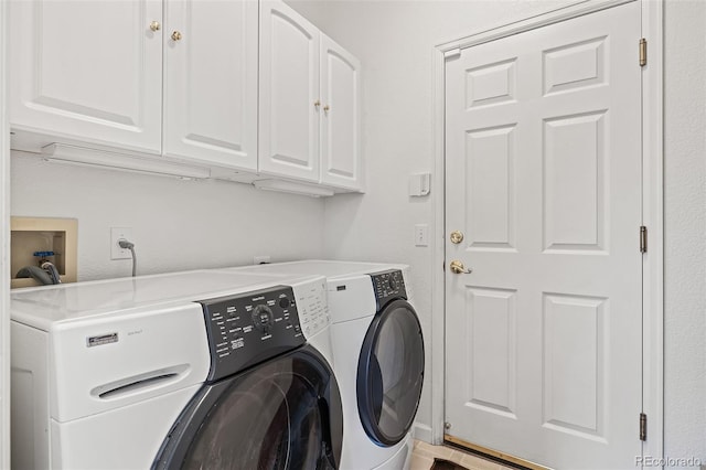clothes washing area with washing machine and clothes dryer and cabinet space