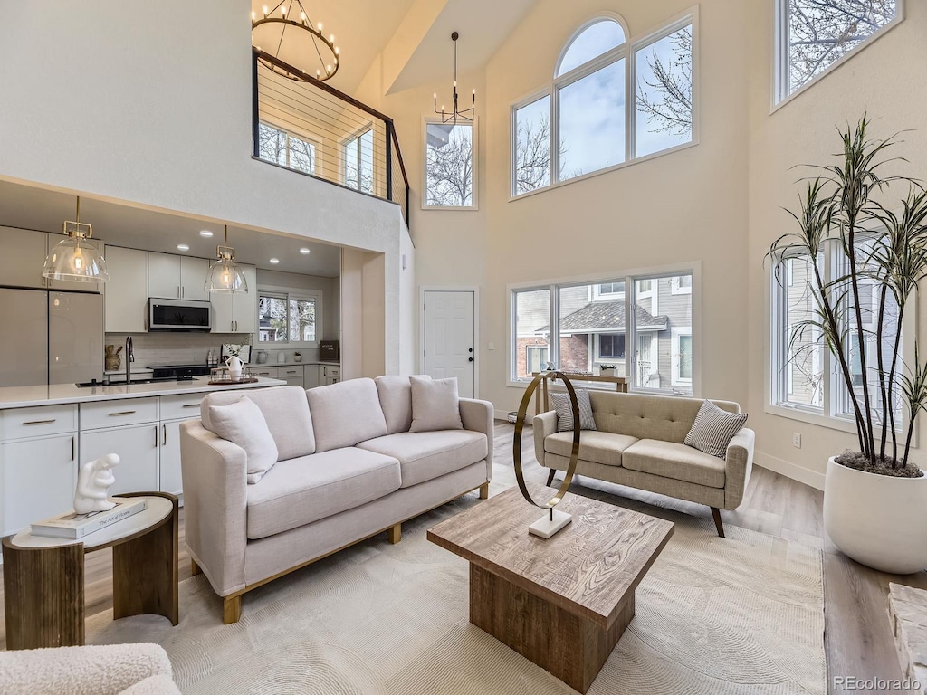 living room with sink, a wealth of natural light, light hardwood / wood-style floors, and a chandelier