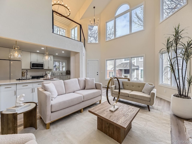 living room with sink, a wealth of natural light, light hardwood / wood-style floors, and a chandelier