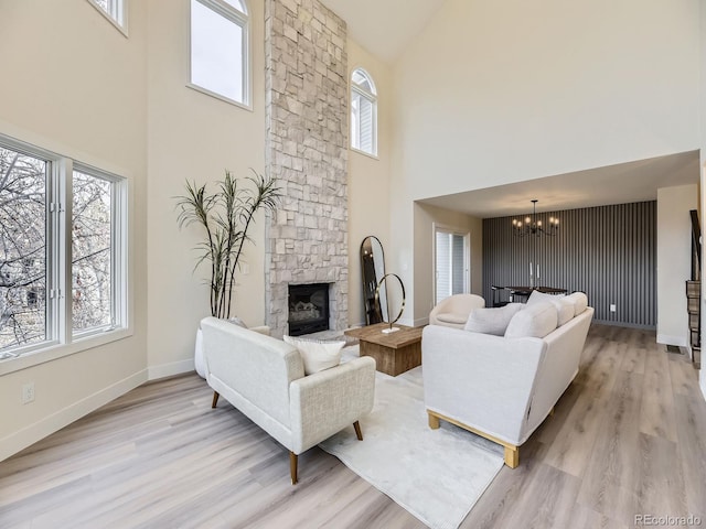 living room with an inviting chandelier, a fireplace, and light hardwood / wood-style flooring