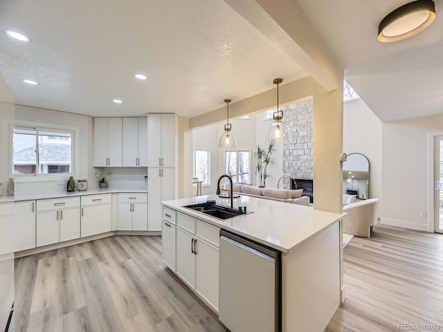 kitchen featuring sink, white cabinetry, decorative light fixtures, light hardwood / wood-style flooring, and dishwashing machine