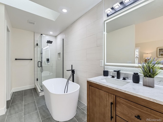 bathroom featuring tile patterned flooring, vanity, shower with separate bathtub, and tile walls