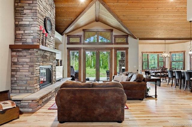 living room featuring wood ceiling, a fireplace, light hardwood / wood-style floors, and a notable chandelier