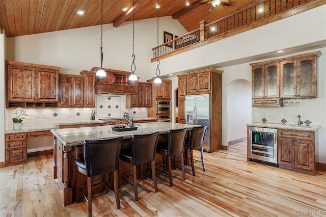 kitchen with an island with sink, beverage cooler, wood ceiling, stainless steel appliances, and light stone countertops