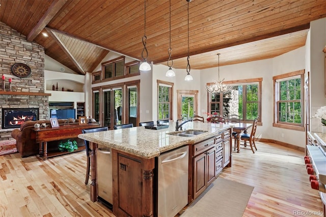 kitchen with decorative light fixtures, wooden ceiling, stainless steel dishwasher, light stone countertops, and a kitchen island with sink