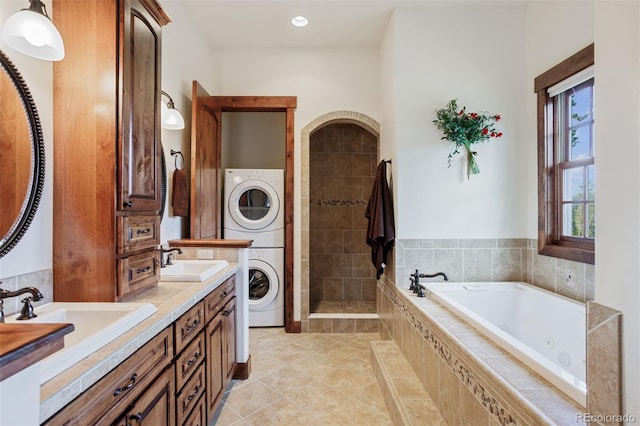 bathroom with stacked washer / drying machine, independent shower and bath, tile patterned flooring, and vanity