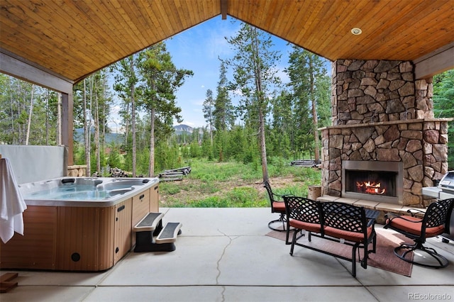 view of patio / terrace with a hot tub and an outdoor stone fireplace