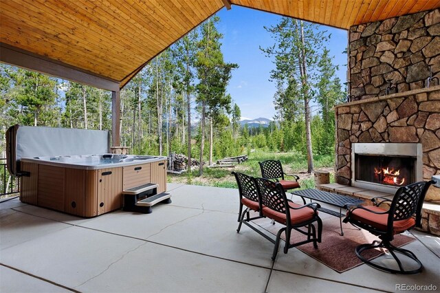 view of patio / terrace with a hot tub and an outdoor stone fireplace