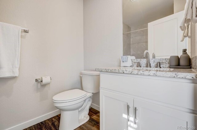2220 E Ln Salle St Unit 108, Colorado Springs, CO 80909 - bathroom featuring wood finished floors, toilet, vanity, baseboards, and tiled shower