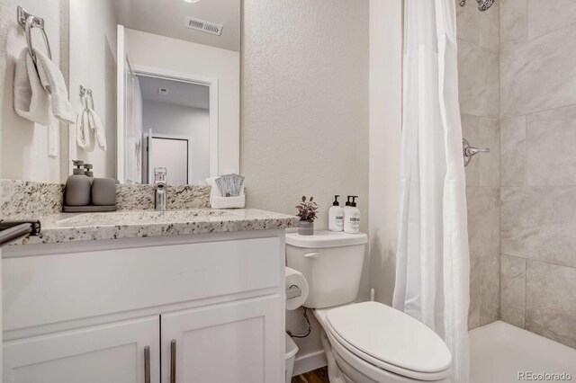 2220 E Ln Salle St Unit 108, Colorado Springs, CO 80909 - bathroom featuring a tile shower, toilet, vanity, and visible vents
