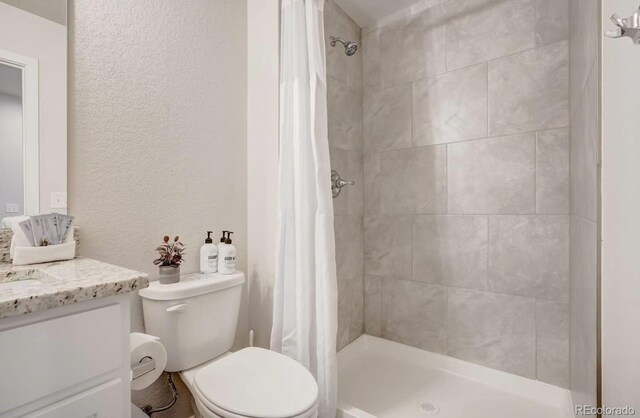2220 E Ln Salle St Unit 108, Colorado Springs, CO 80909 - full bath featuring a textured wall, vanity, a shower stall, and toilet