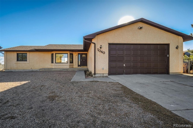 ranch-style house featuring a garage, roof with shingles, concrete driveway, and stucco siding