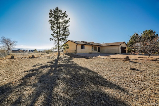 back of property with a garage, fence, and stucco siding