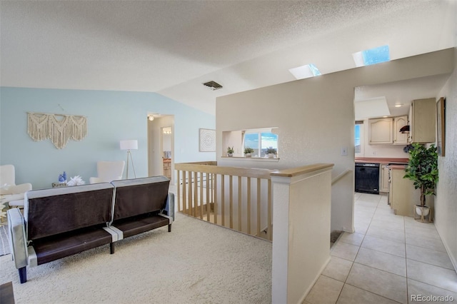 hallway with lofted ceiling, visible vents, light tile patterned flooring, a textured ceiling, and an upstairs landing