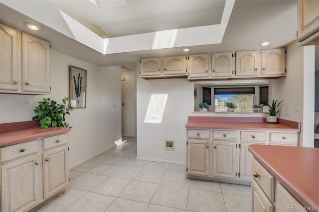 kitchen featuring a skylight, light countertops, a tray ceiling, and light tile patterned floors