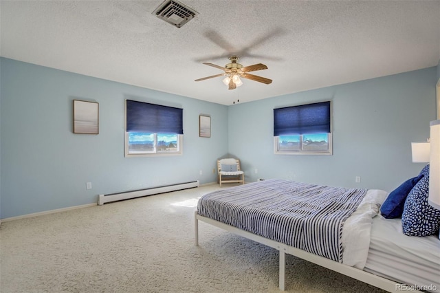 bedroom with a baseboard heating unit, carpet floors, a textured ceiling, and visible vents