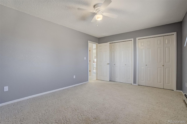 unfurnished bedroom featuring a textured ceiling, carpet, baseboards, and multiple closets