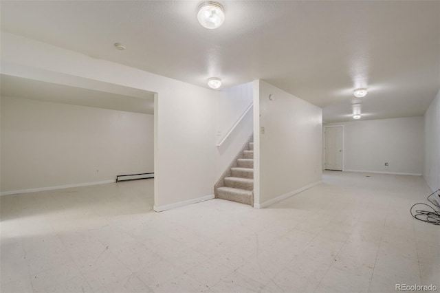 finished basement with a baseboard heating unit, baseboards, stairs, and tile patterned floors