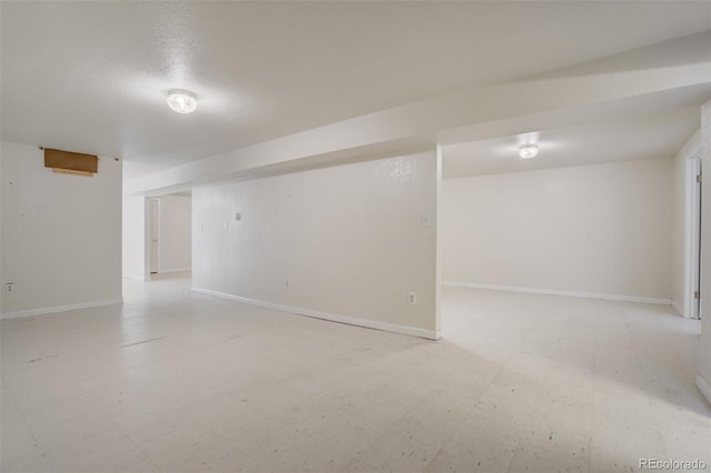 finished basement featuring a textured ceiling and baseboards