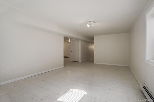 spare room featuring light floors, a baseboard radiator, and baseboards