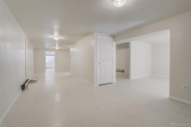 below grade area featuring baseboard heating, baseboards, and light floors