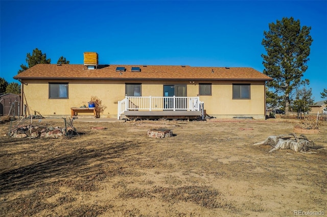 back of house with an outbuilding, a deck, a storage shed, and stucco siding