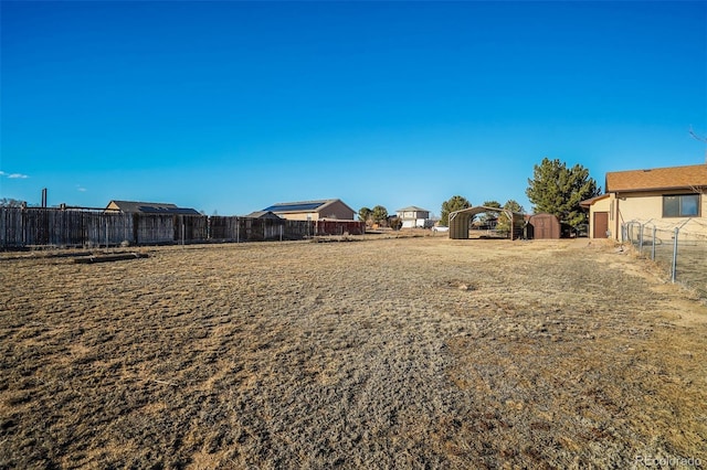 view of yard featuring a storage shed, fence, and an outdoor structure