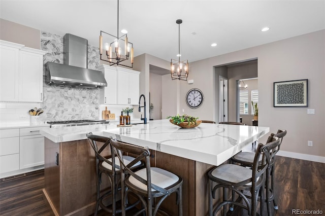 2144 Bellcove Dr, Castle Pines, CO 80108 - kitchen with wall chimney range hood, dark wood-type flooring, a large island with sink, white cabinets, and tasteful backsplash
