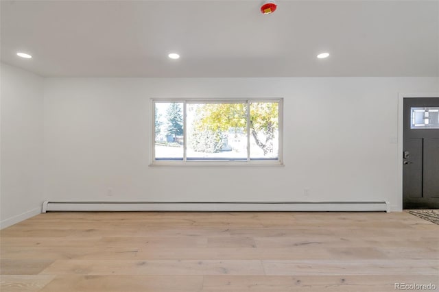 spare room with a baseboard radiator and light hardwood / wood-style flooring