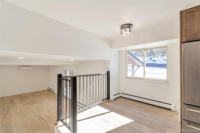 interior space with a wall mounted air conditioner, light wood-type flooring, and baseboard heating