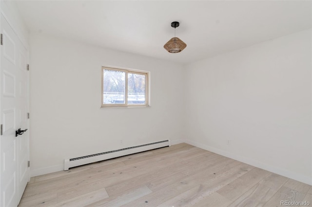 empty room with light hardwood / wood-style flooring and a baseboard heating unit