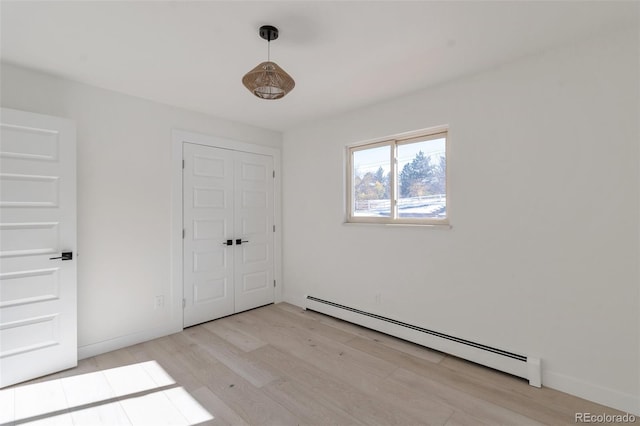 spare room with baseboard heating and light hardwood / wood-style flooring