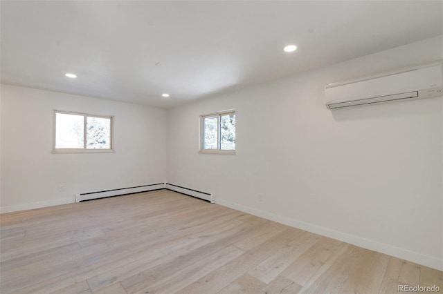 unfurnished room featuring a baseboard heating unit, an AC wall unit, a wealth of natural light, and light hardwood / wood-style flooring