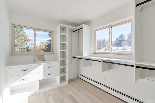 spacious closet with a baseboard radiator and light hardwood / wood-style flooring