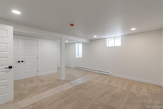 basement featuring light carpet and a baseboard heating unit