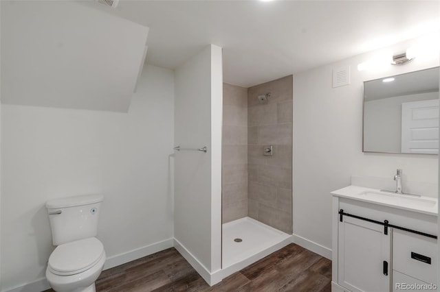 bathroom featuring tiled shower, toilet, vanity, and hardwood / wood-style flooring