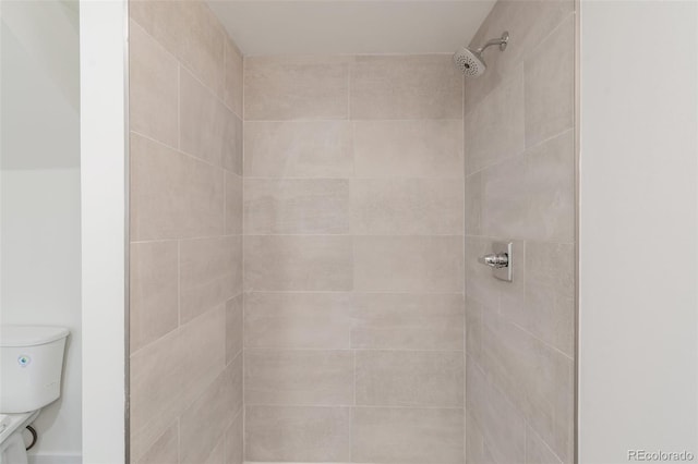 bathroom featuring tiled shower and toilet