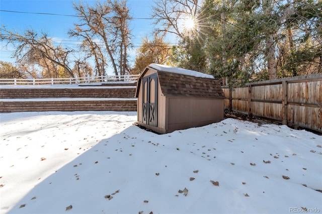 snowy yard featuring a storage unit