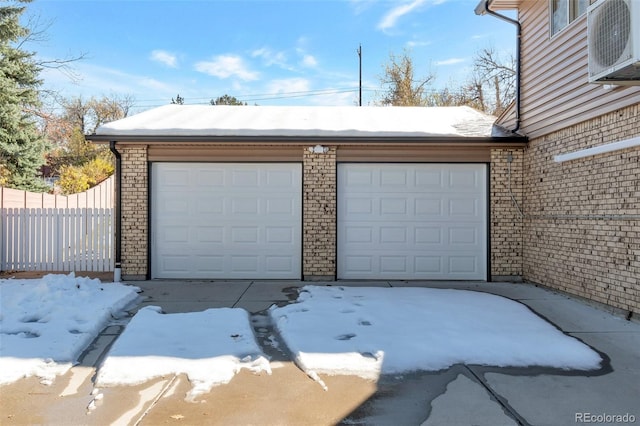 snow covered garage featuring ac unit