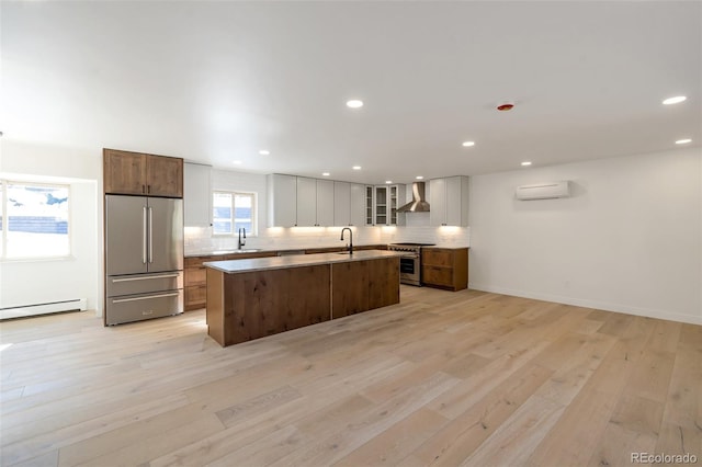 kitchen featuring stainless steel appliances, light hardwood / wood-style flooring, a kitchen island with sink, and a wall unit AC